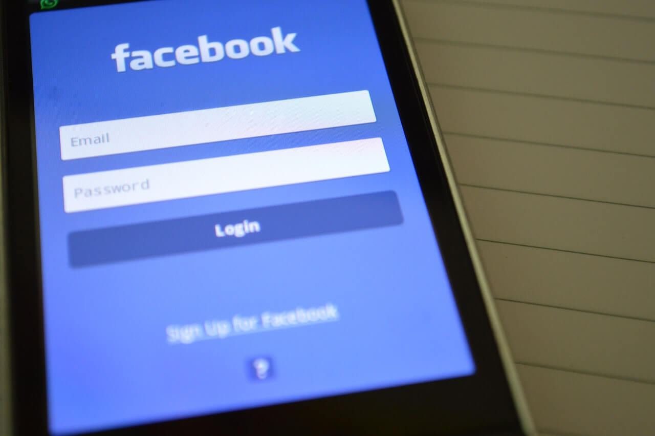 A closeup of a cell phone showing the login page for the Facebook Mobile app.