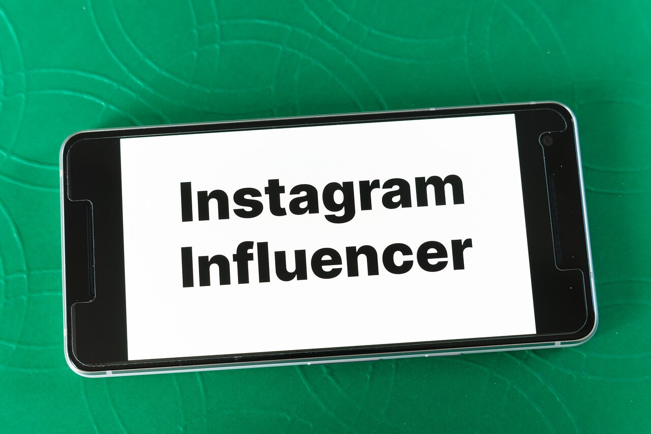 A mobile screen on a green background saying *instagram influencer* in black and on a white screen.